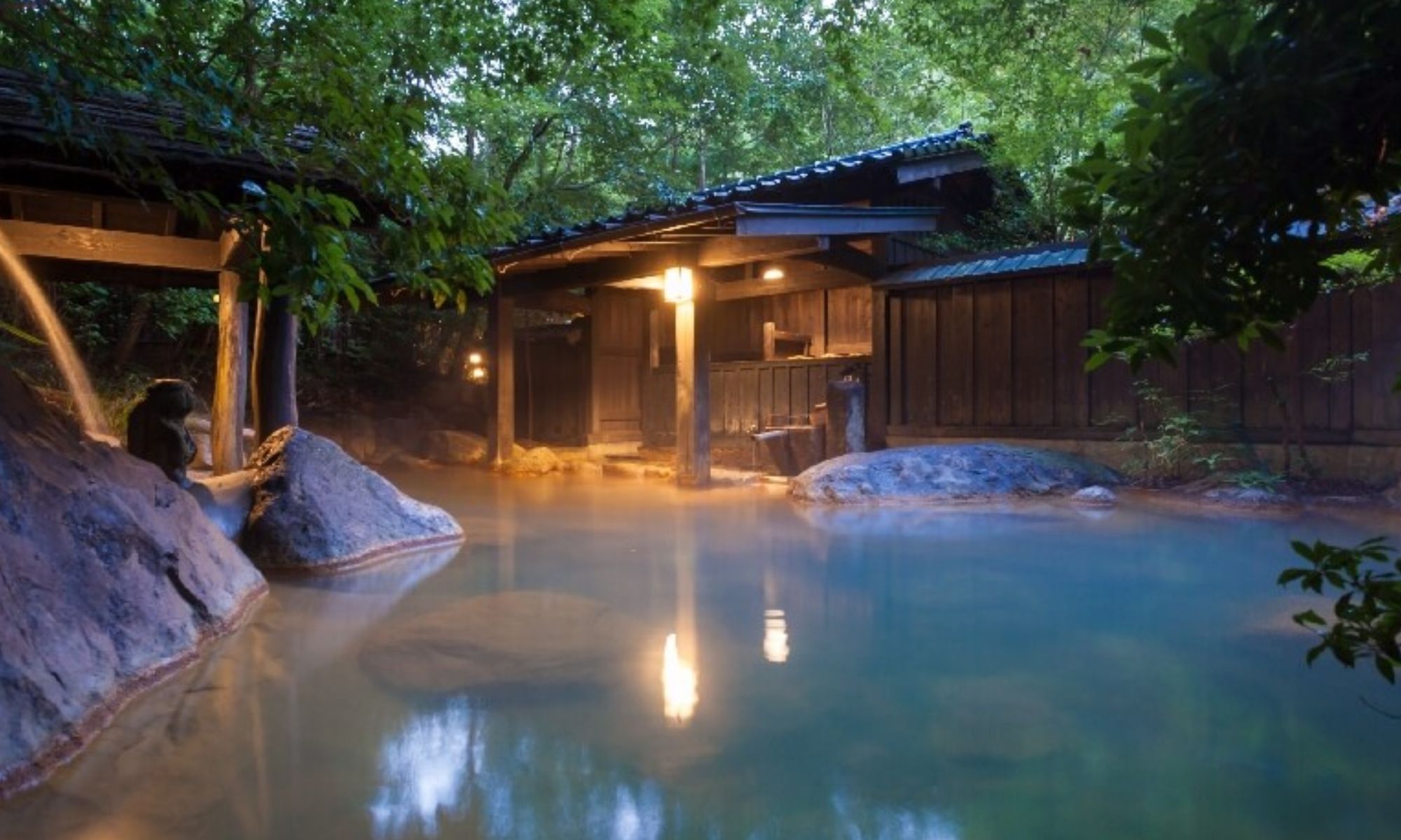Quiet mixed-gender outdoor hot spring surrounded by mountains and steam